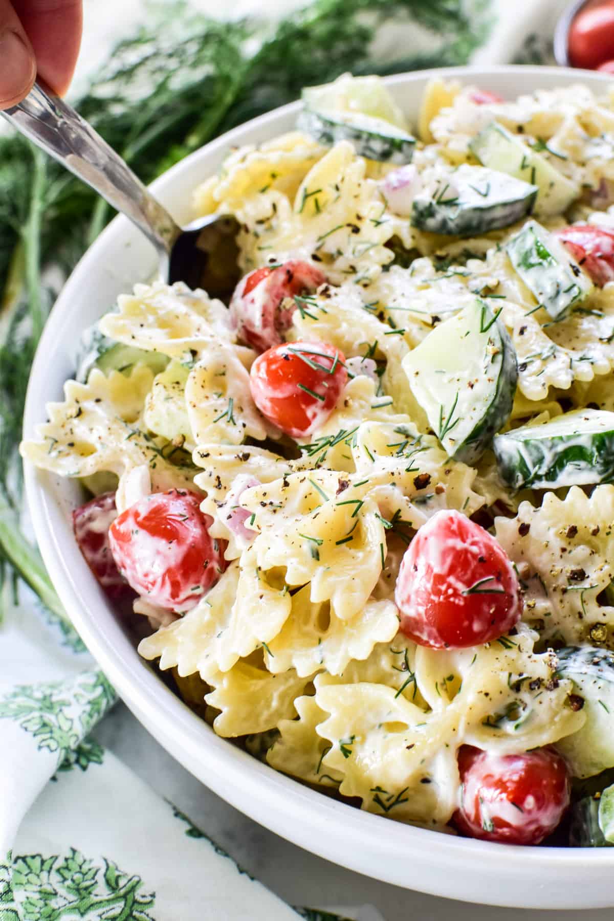 Close up of Cucumber Pasta Salad in a white serving bowl with a spoon