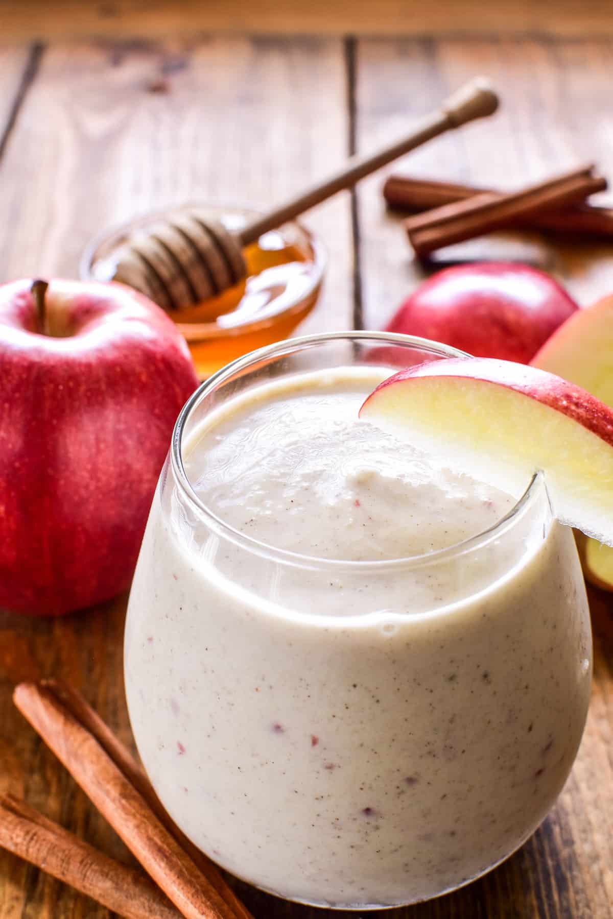 Apple Smoothie in a glass with an apple slice garnish and fresh apples in the background