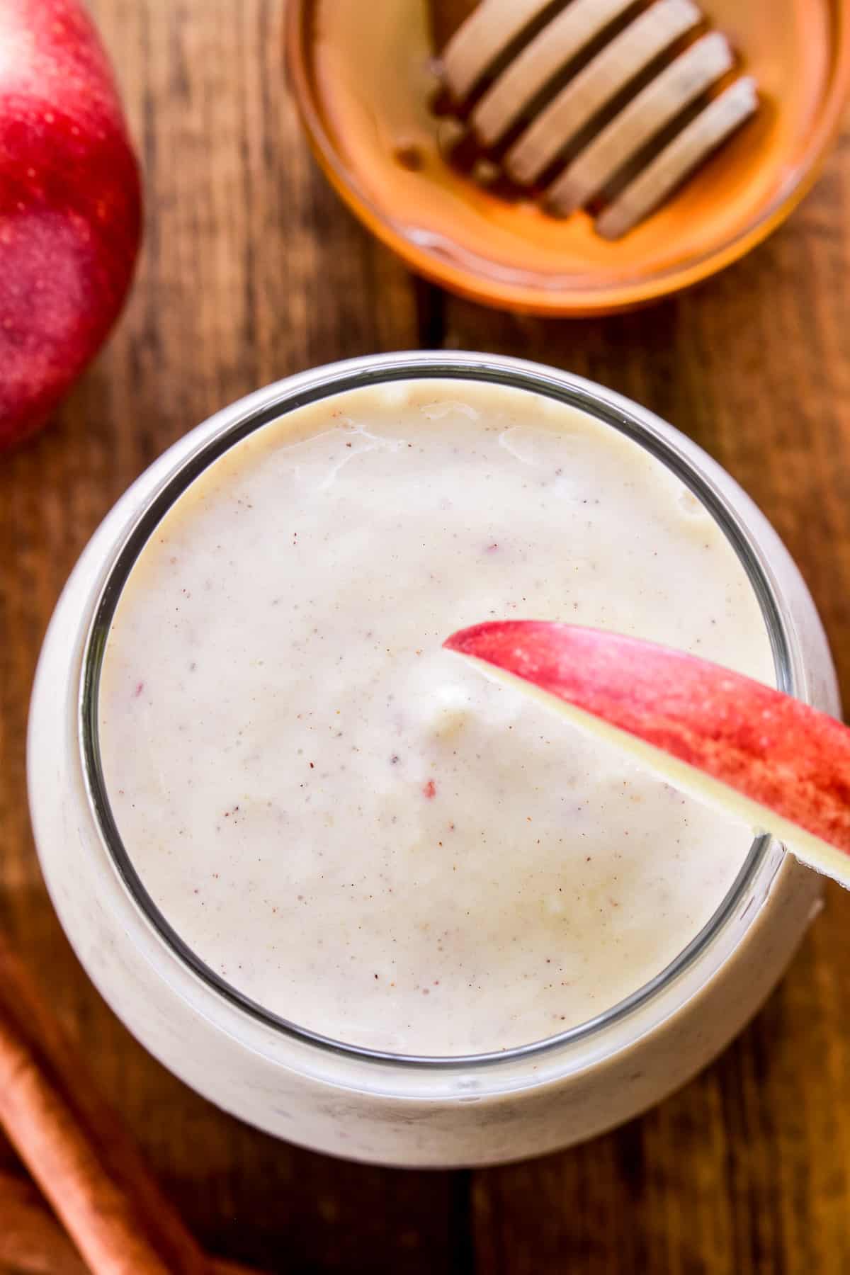 Overhead image of Apple Smoothie in a glass with cinnamon sticks and honey