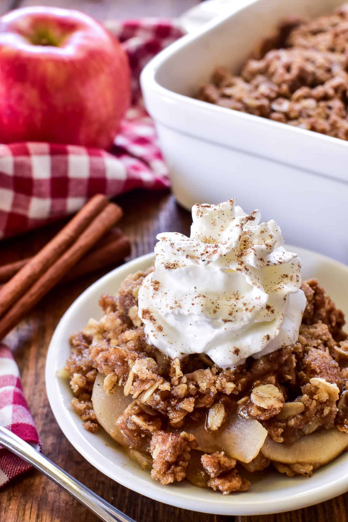 Apple Pear Crisp on a small white plate with whipped cream and cinnamon