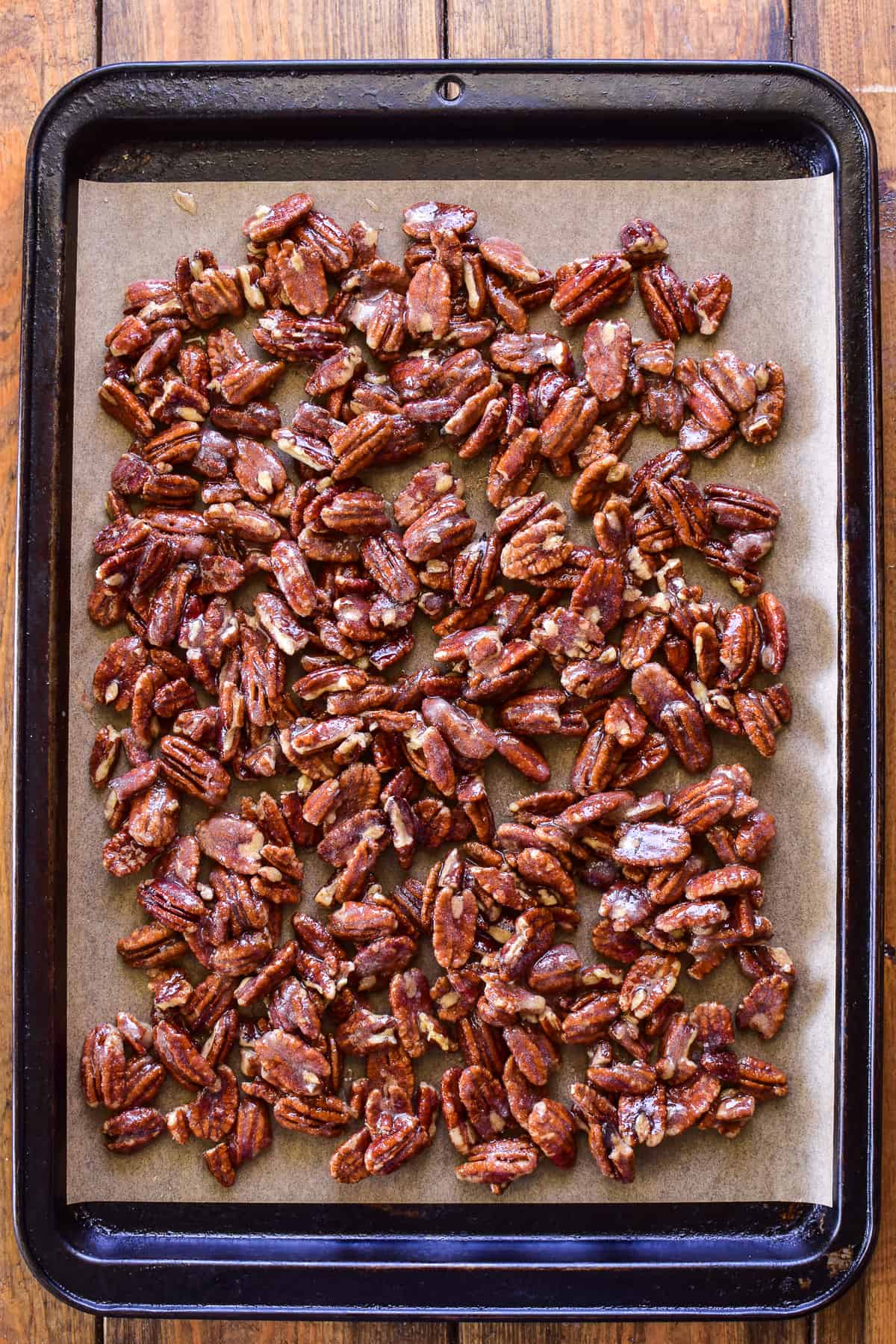 Pre-baked candied pecans on a baking sheet 