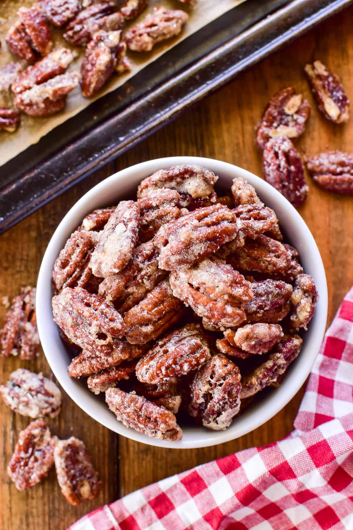 Candied Pecans in a white bowl with a red & white gingham towel