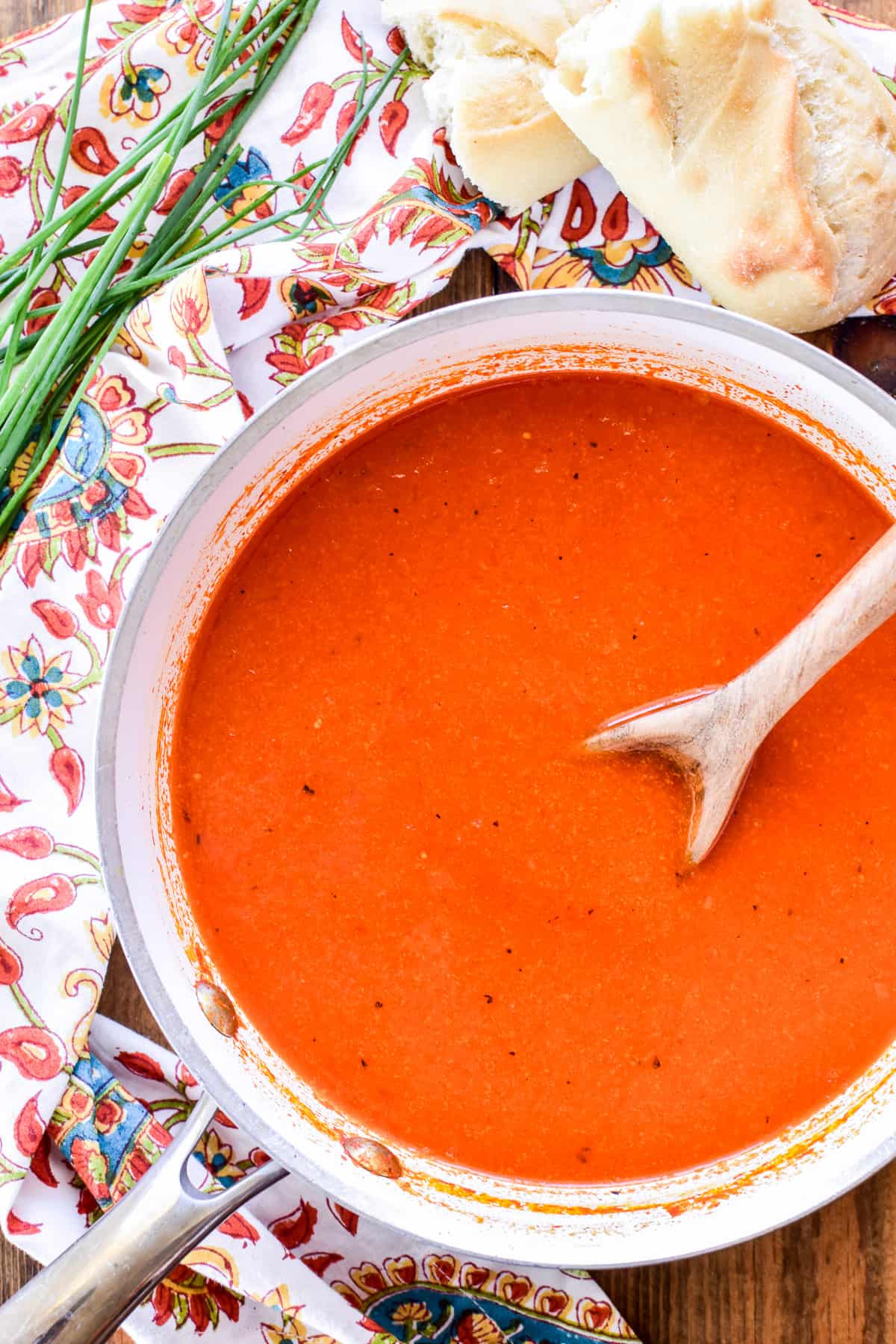 Roasted Red Pepper Soup in a saucepan with a wooden spoon