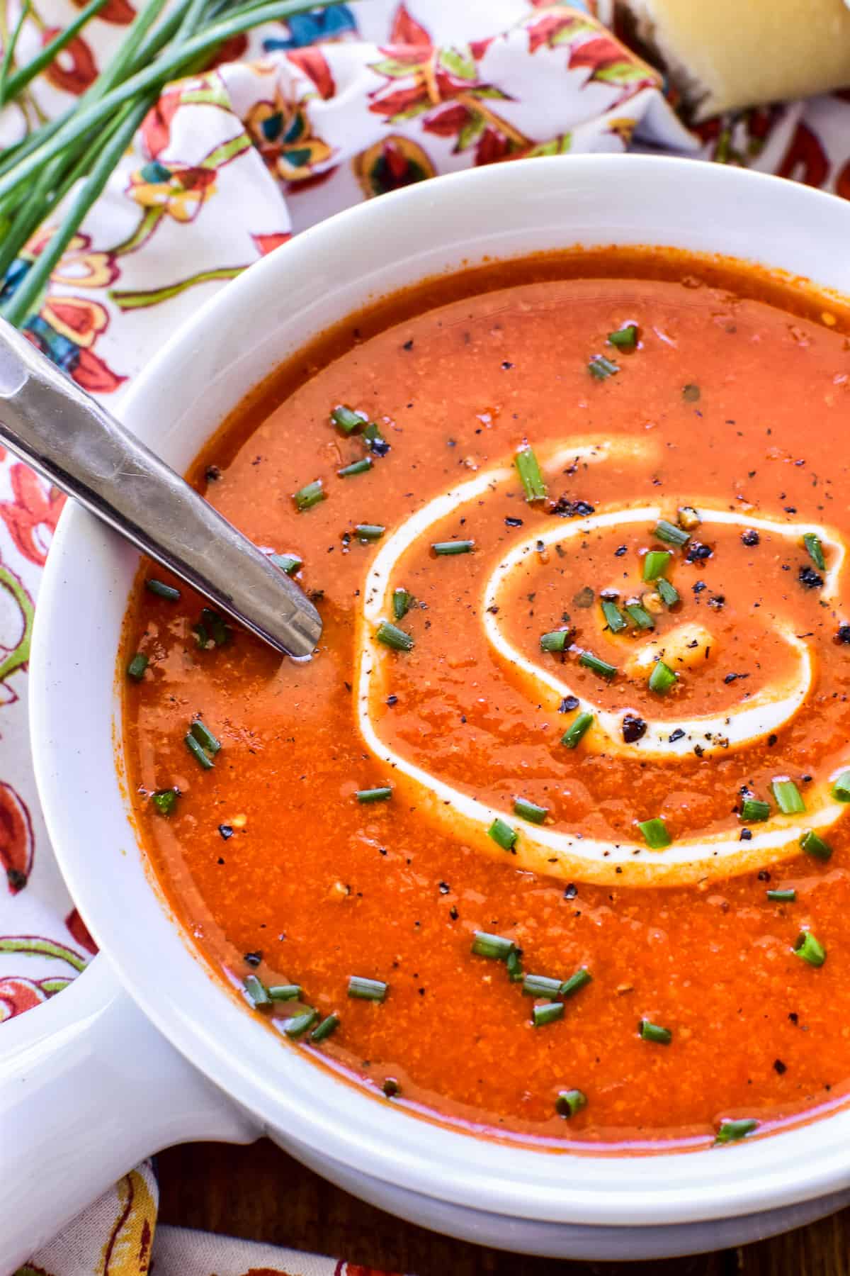 Close up of Roasted Red Pepper Soup in a white bowl with sour cream and chives