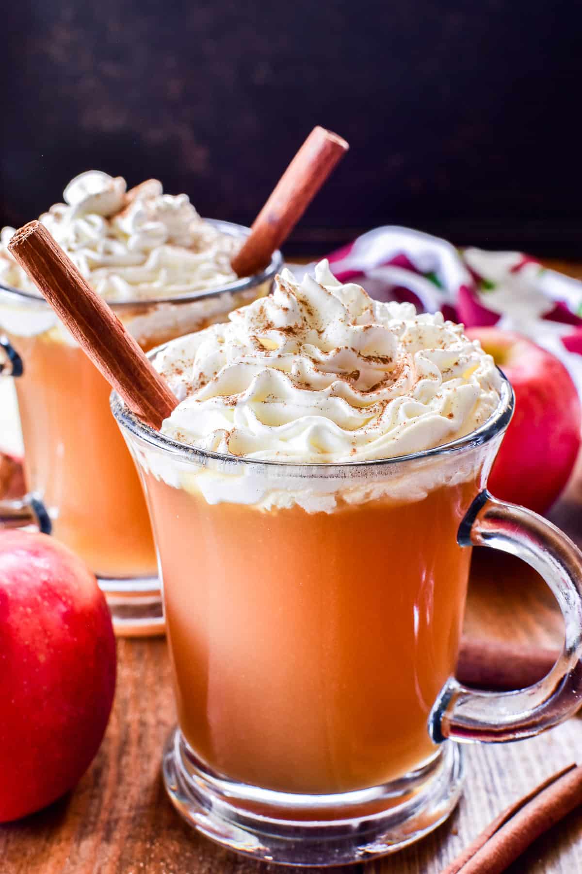 Spiked Apple Cider in a glass mug with whipped cream and cinnamon sticks