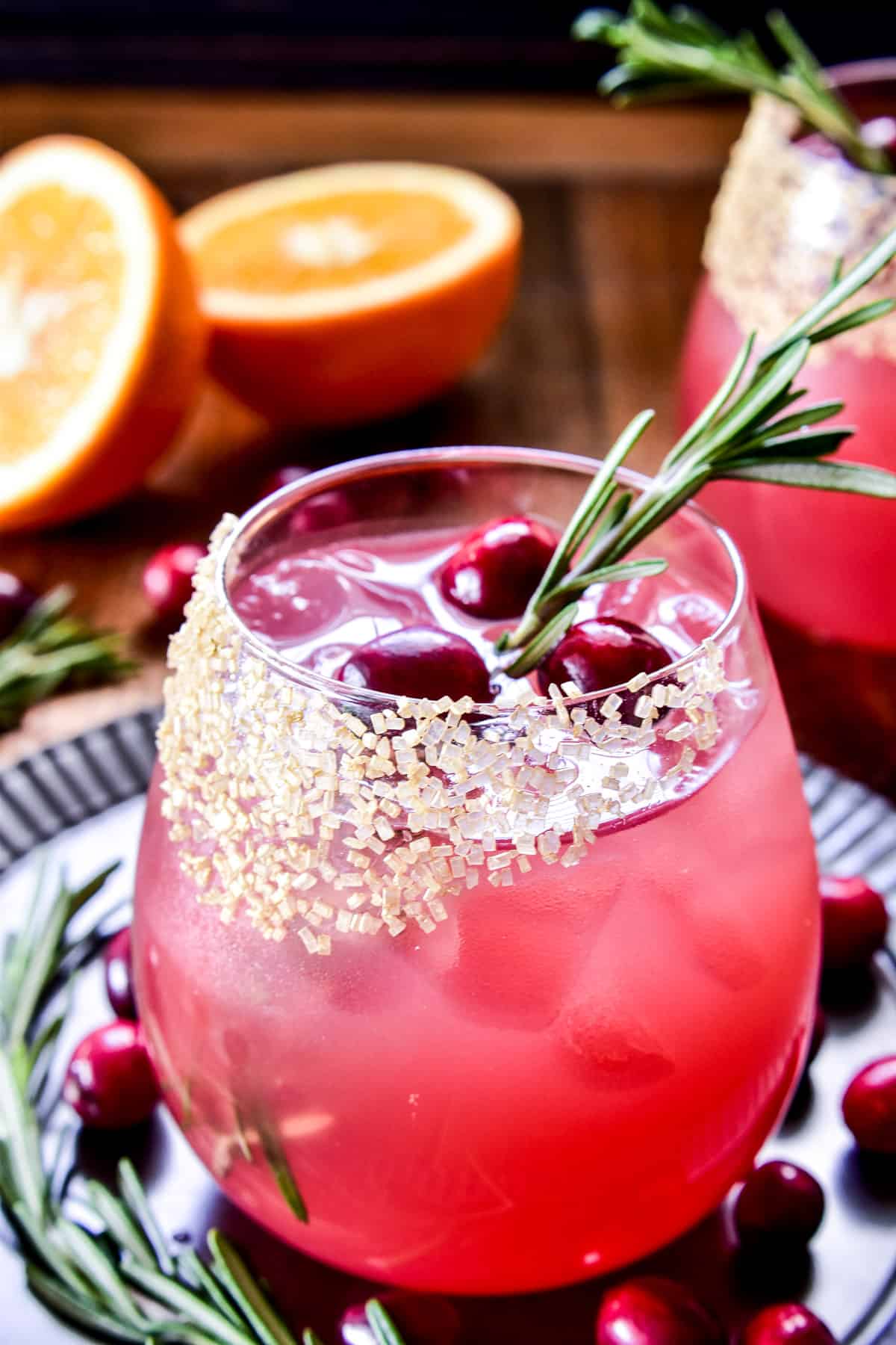 Cranberry Margarita with a gold sugared glass, fresh cranberries, and fresh rosemary