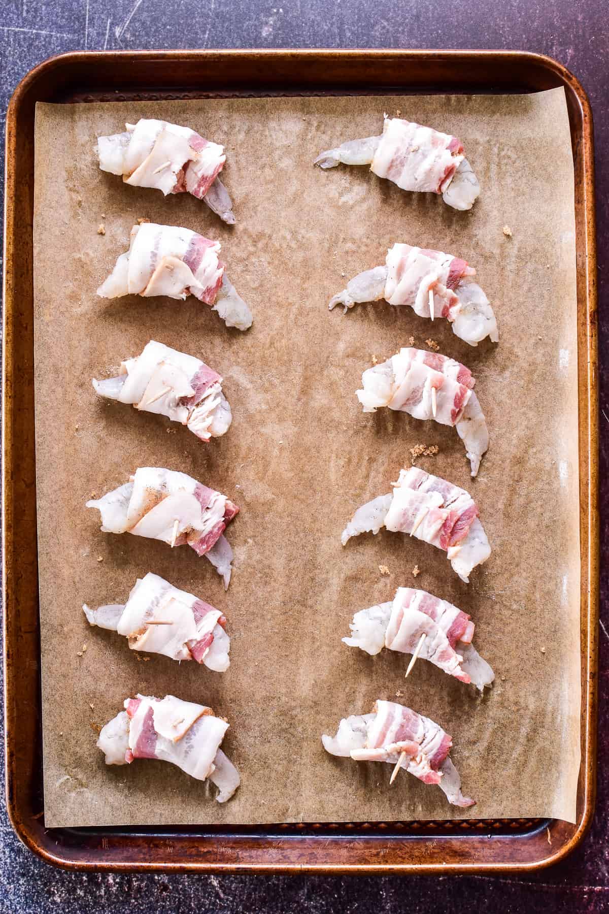 Uncooked Bacon wrapped shrimp on a baking sheet