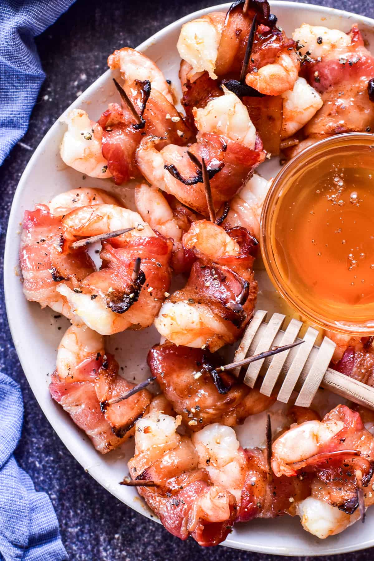 Overhead image of Bacon Wrapped Shrimp on a white plate with a blue towel