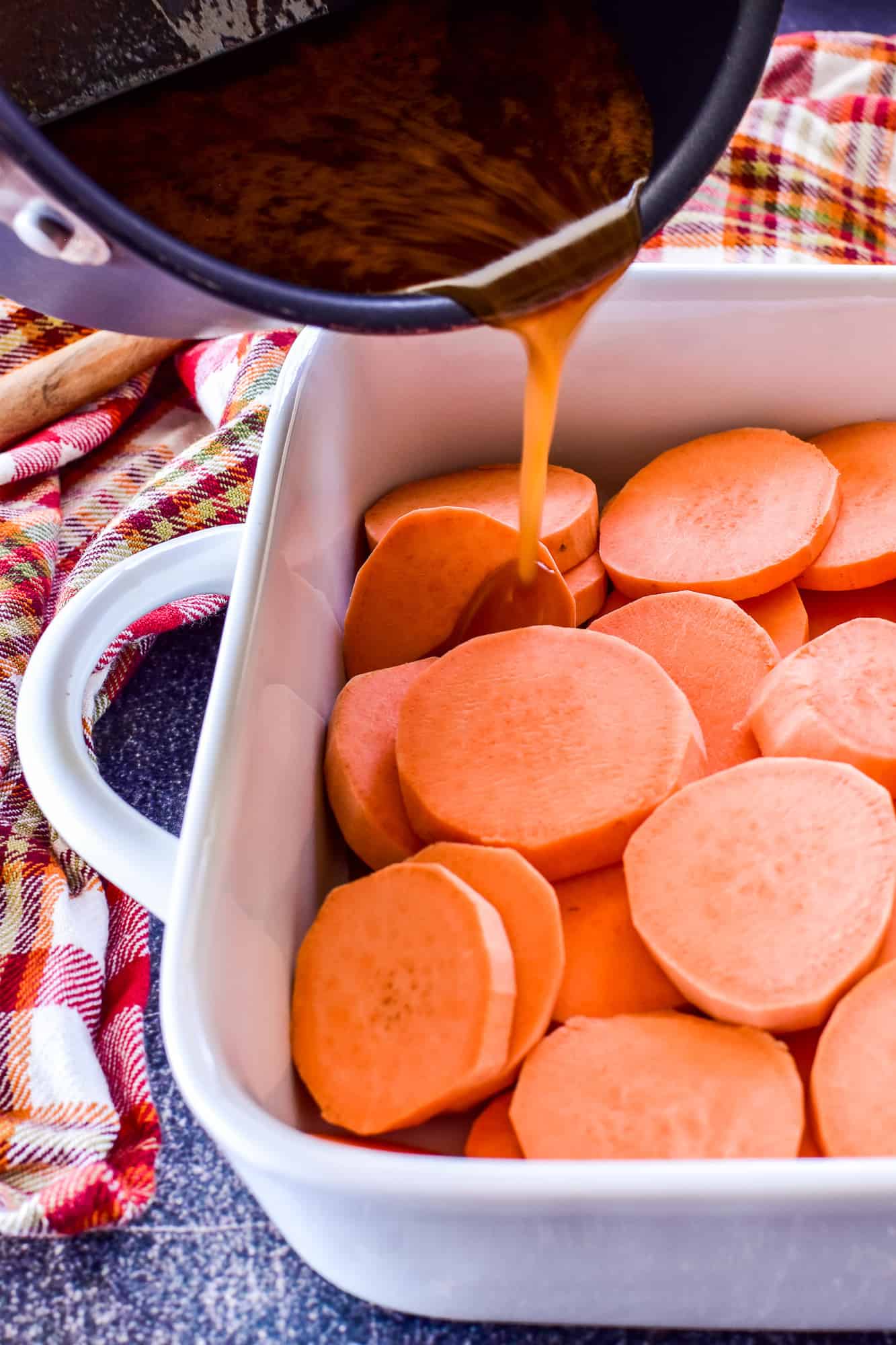 Sauce pouring over sliced sweet potatoes for Candied Yams