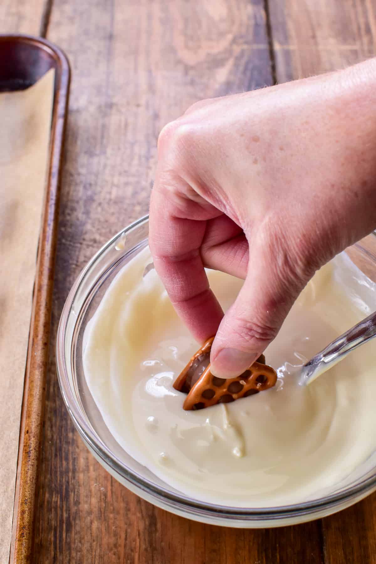 Dipping stuffed pretzels into melted white chocolate