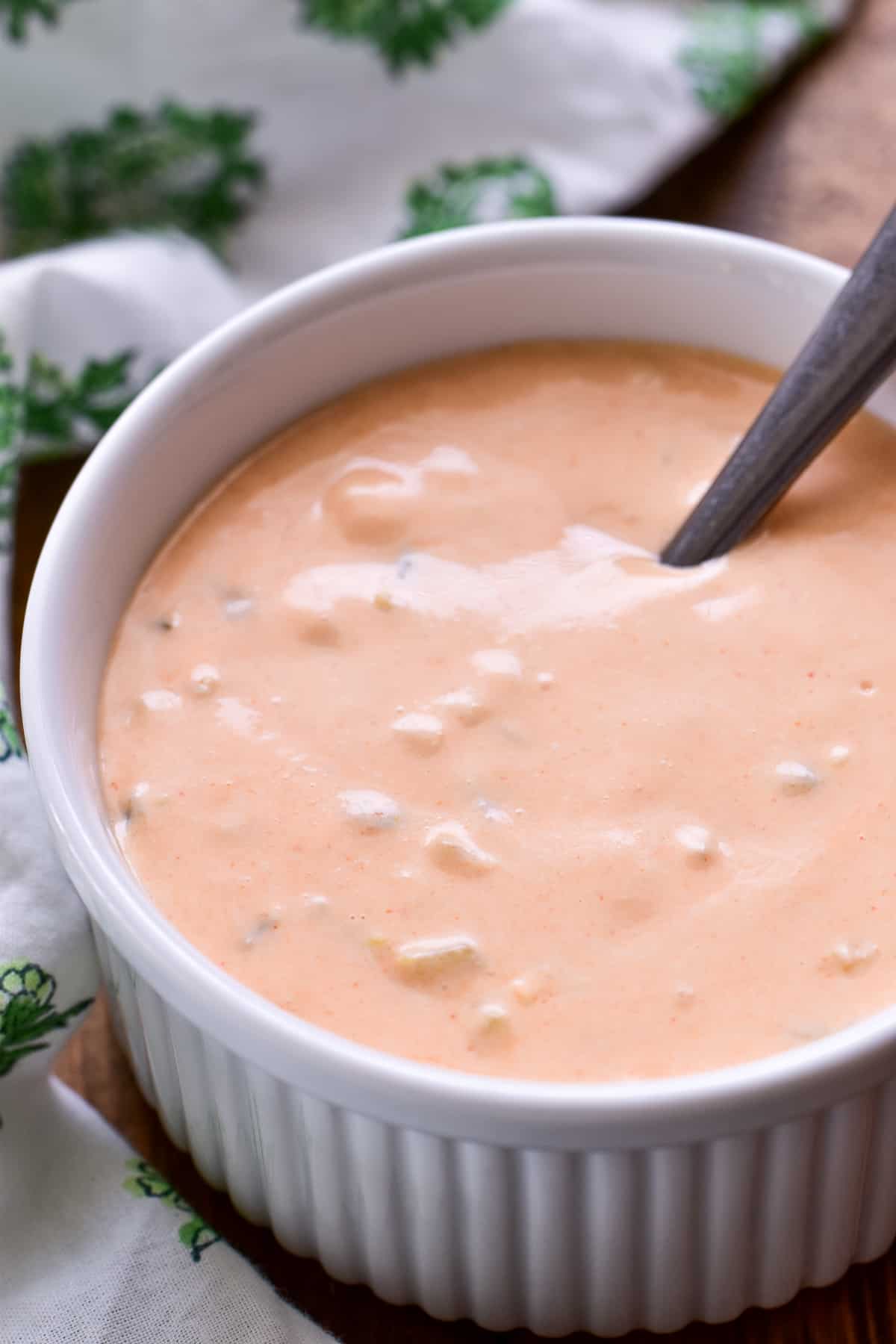 Side view of Big Mac Sauce in a small white bowl with a white and green patterned towel