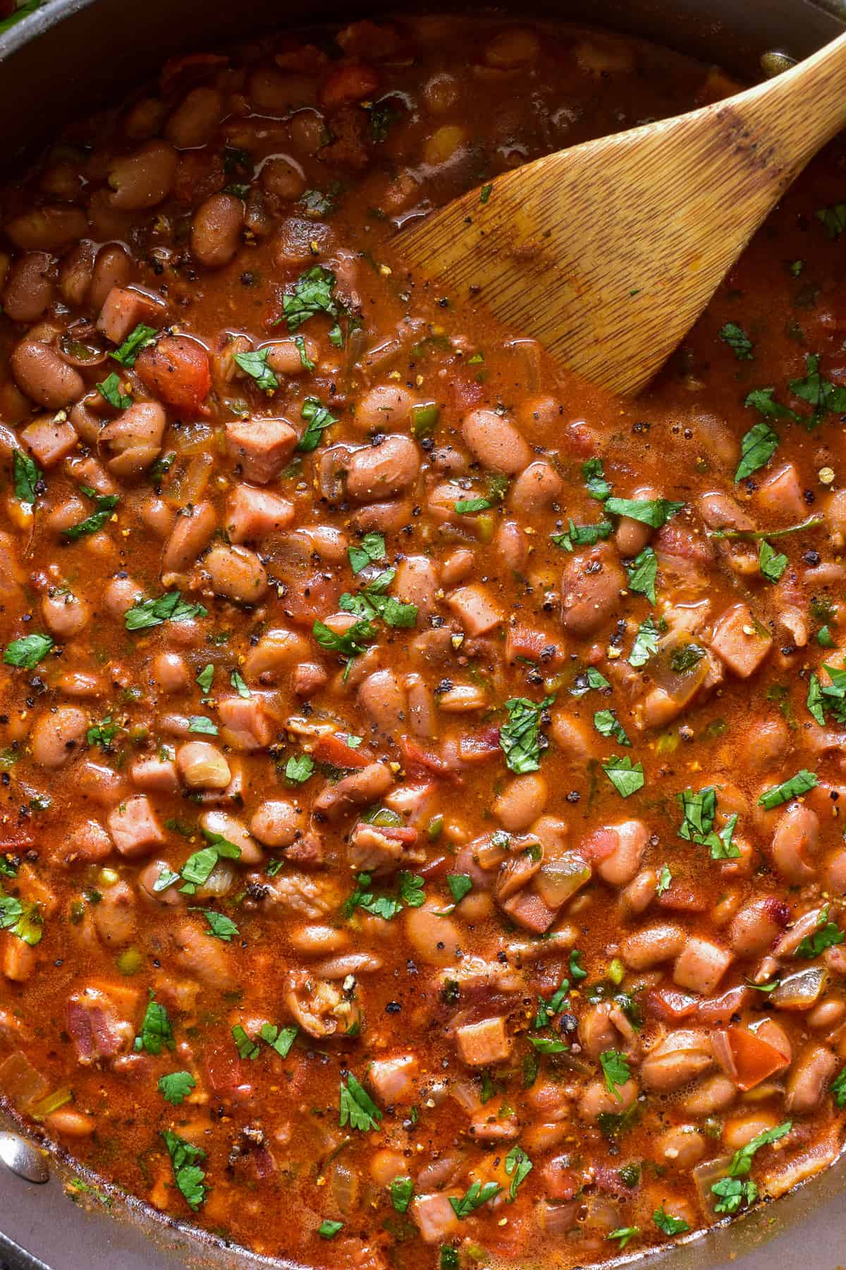 Close up of Charro Beans garnished with fresh cilantro in a large pot