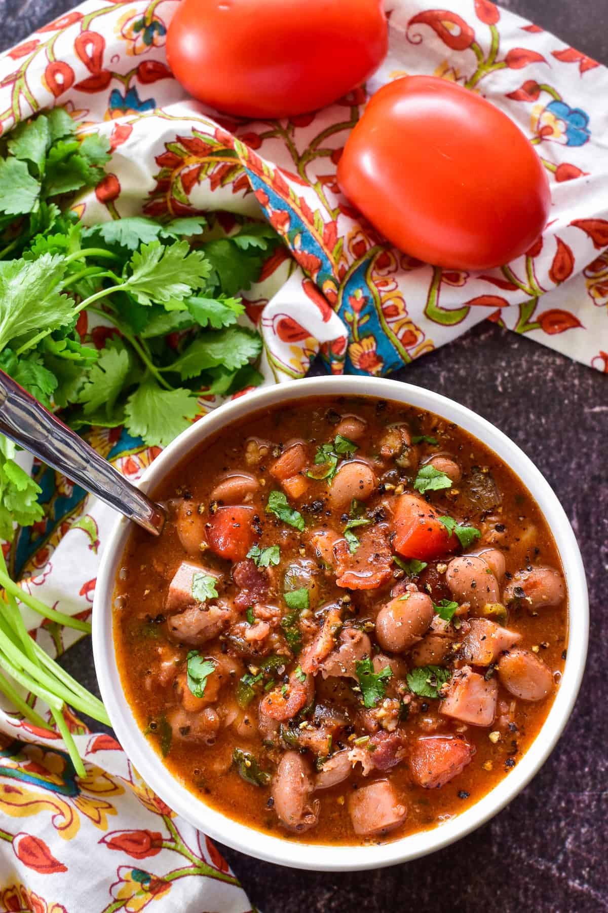 Charro Beans in a small white bowl and a patterned towel in the background