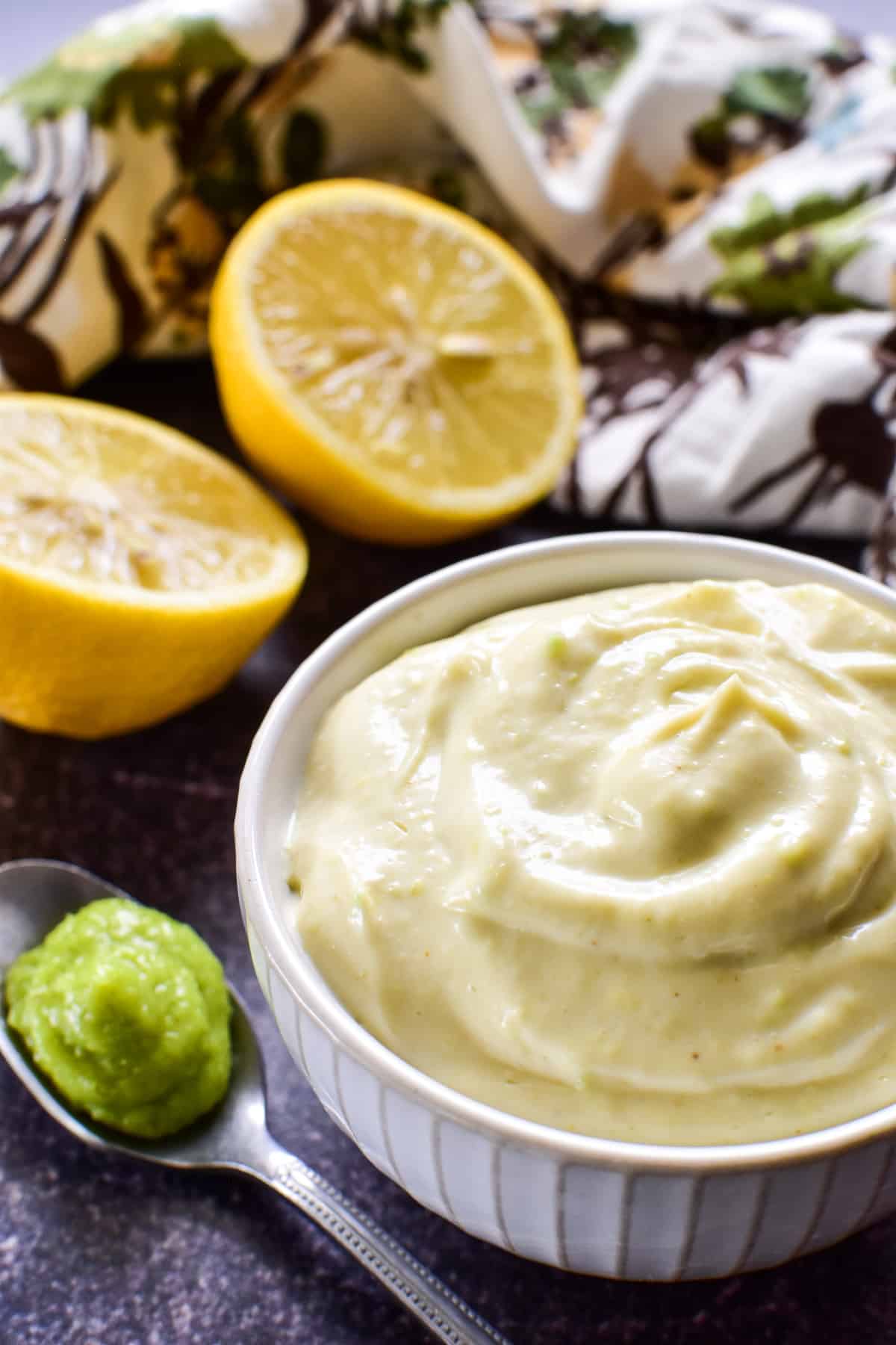 Homemade Wasabi Mayo in a small white bowl with a cut lemon and floral patterned towel in the background