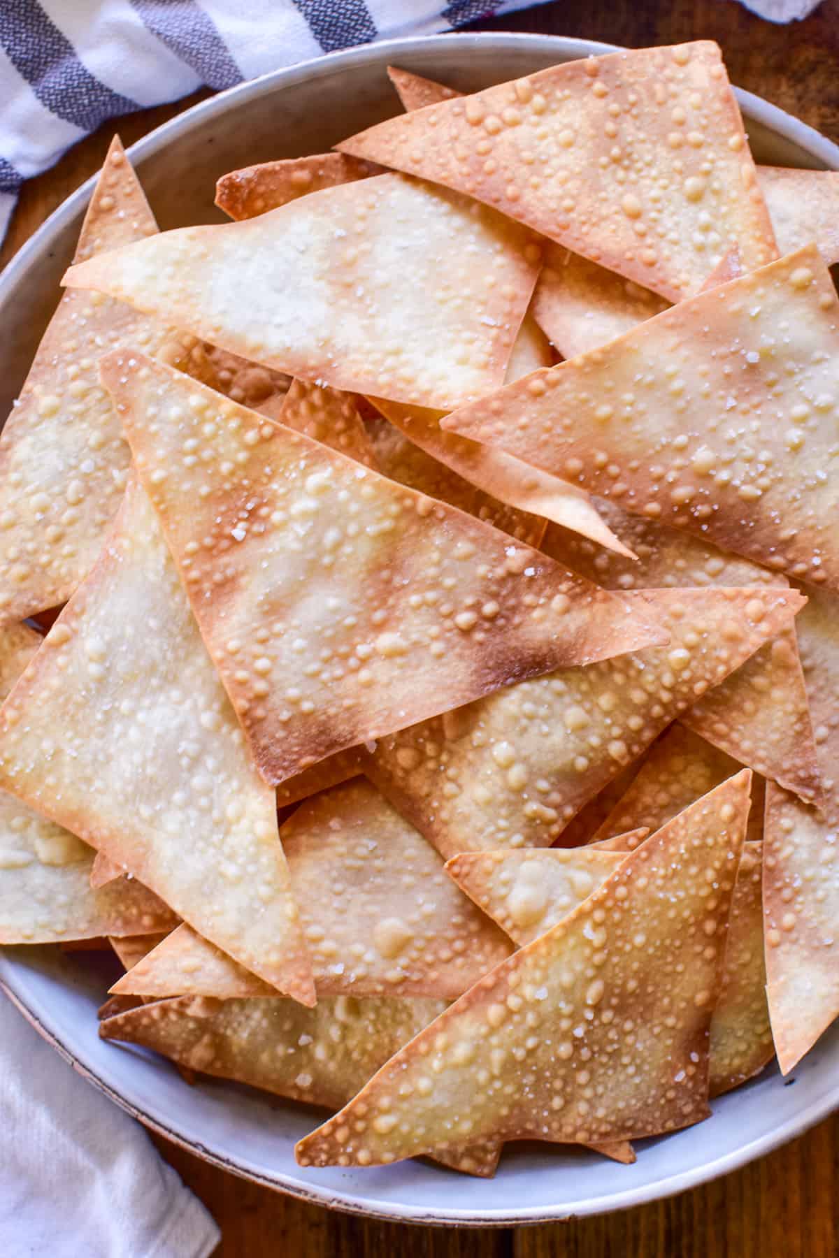 Close-up of Wonton Chips in a gray bowl with a gray and white striped towel