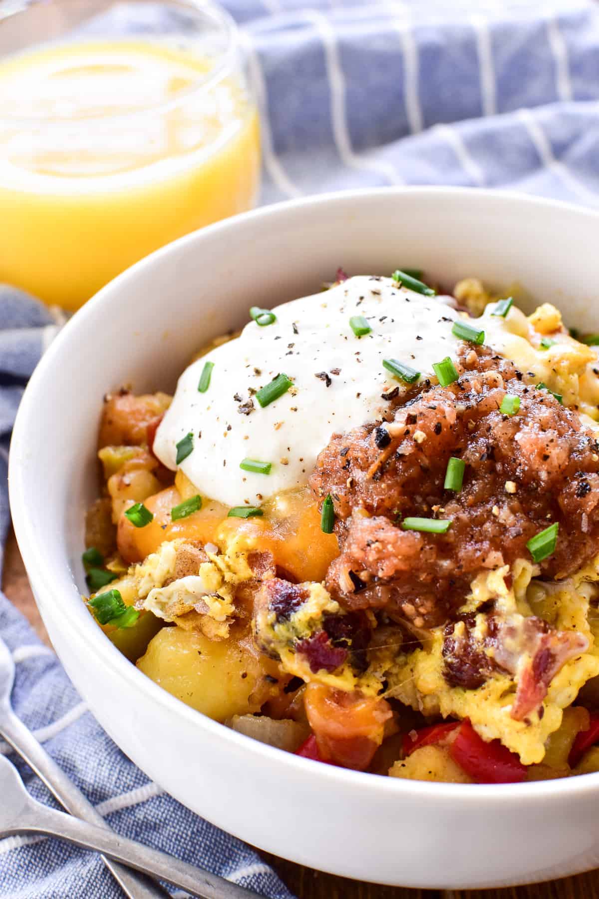 Side view of Breakfast Bowl with potatoes, eggs, sausage, bacon, cheese, salsa, and sour cream